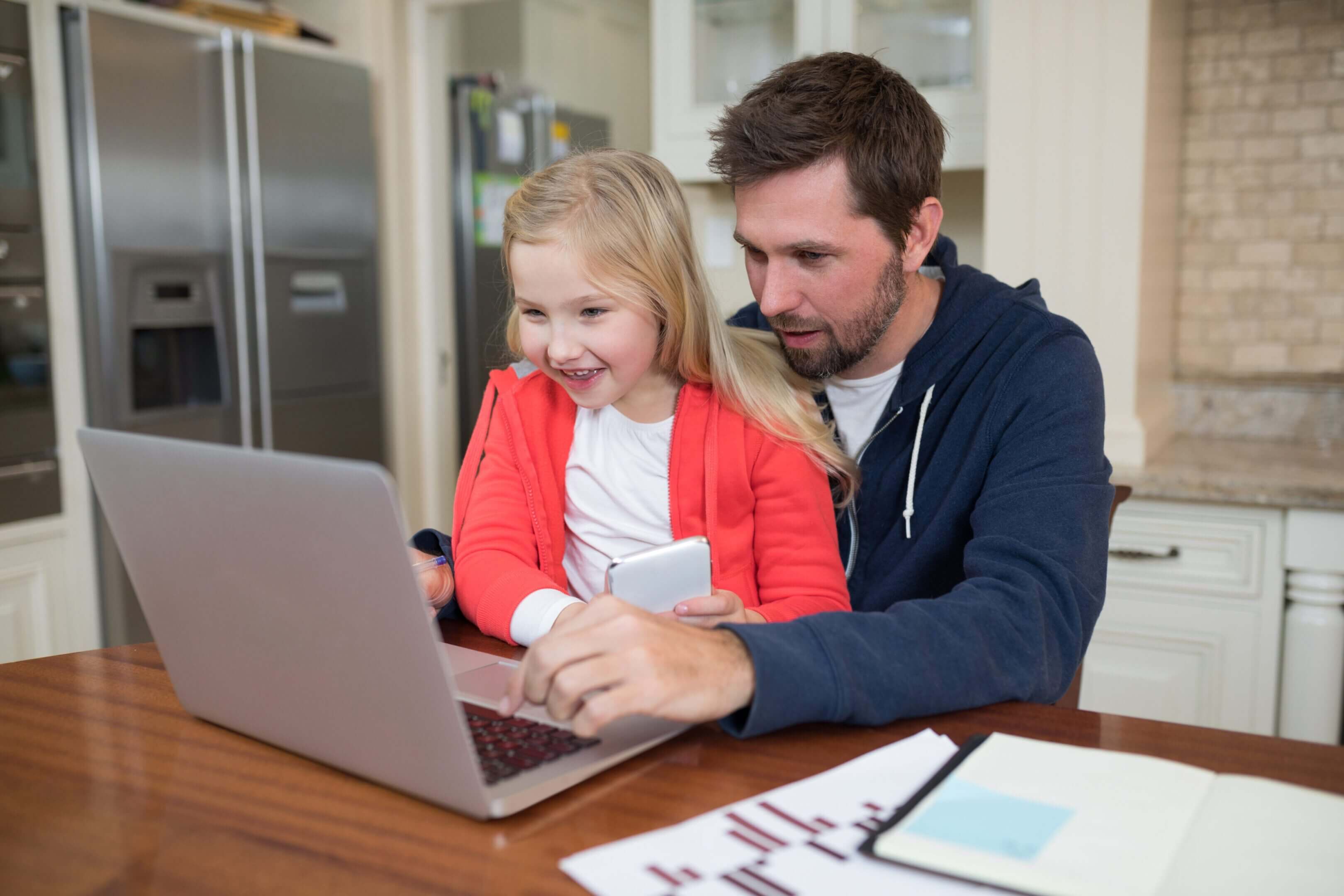 Father and daughter using a laptop together at home.